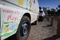 Closeup shot of "vamos a la playa" writing and colorful flower drawings on white van on sunny day Royalty Free Stock Photo