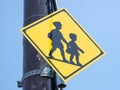 Closeup shot of a yellow diamond shaped school zone street sign on a black pole