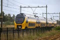 Closeup shot of a yellow intercity train riding during heavy rain in Limburg, Netherlands