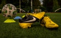 Closeup shot of a yellow Nike Ctr360 Maestri Soccer shoes and an Adidas ball in the field