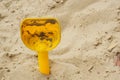 Closeup shot of a yellow plastic toy shovel in the sand Royalty Free Stock Photo
