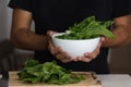 Closeup shot of a young man holding a bunch of spinach in a bowl
