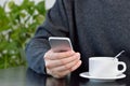 young man using a cellphone and drinking a coffee while sitting in a cafe Royalty Free Stock Photo