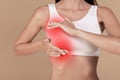 Closeup shot of young woman pulping her breast, sore zone highlighted with red, cropped, copy space Royalty Free Stock Photo