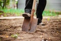 Closeup of a shovel and a man digging a hole at the garden for the plant to be placed inside. Old man`s foot digging a pit at his