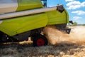 Closeup side view Big powerful industrial combine harvester machine reaping golden ripe wheat cereal field and grinding Royalty Free Stock Photo