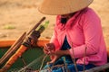 Closeup Side View Woman in Hat Repairs Fishing Net in Round Boat