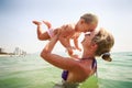 closeup side-view mother holds small daughter both smile in sea