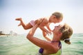 Closeup side-view mother holds small daughter both smile in sea