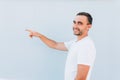 Closeup side view portrait of young man, laughing, pointing with finger at someone or something, isolated on blue background. Posi Royalty Free Stock Photo