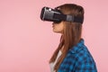 Closeup side view of serious gamer girl in checkered shirt wearing vr headset, playing virtual reality game