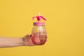 Closeup side view shot of woman hand holding pink glass jar mug with straw for cocktail or smoothie Royalty Free Stock Photo