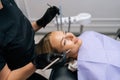Closeup side view of unrecognizable female dentist in gloves examining teeth of smiling young woman using dental Royalty Free Stock Photo