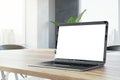Closeup side view of a wooden office desk with white blank screen modern laptop, on city view window background in cozy interior, Royalty Free Stock Photo