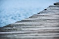 Closeup of the side of a wooden pier running diagonally across the frame with the lake visible in the background Variation 1