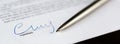 Closeup of signature and ballpoint pen with on document. Focus on signature Royalty Free Stock Photo