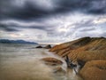 Silky smooth water on the beach with dark cloudy sky above. Royalty Free Stock Photo