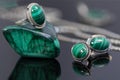 Closeup silver earrings and ring with malachite on top of malachite stone piece on background of silver chain on black acr Royalty Free Stock Photo