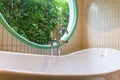 Closeup of silver faucet for Hot water Cold water on a white bathtub with circular windows and trees in the background Royalty Free Stock Photo