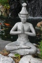 Closeup of a silver praying Buddha statue near the pond Royalty Free Stock Photo