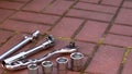 Closeup of a silver set of wrenches, nuts and bolts on the ground outdoors