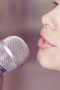 Closeup of singing caucasian child girl. Young girl emotionally sings into the microphone, holding it with hand. Royalty Free Stock Photo
