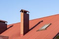 Closeup of skylight and brick chimney on the metal tile roof under blue sky Royalty Free Stock Photo