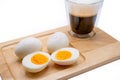 Closeup of sliced eggs and a glass of frothy black coffee on a wooden board