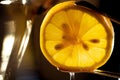 Closeup of a sliced lemon being squeezed by tongs over a dish