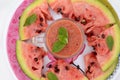 Closeup sliced red ripe watermelon with juice and mint in the plate isolated on white background Royalty Free Stock Photo