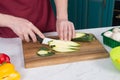 Closeup of sliced zucchini on table. Close up of hands slicing green vegetable with white knife. Closeup of men cutting green vego