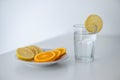 Closeup of slices of lemon and orange, on a plate and a glass of water, white background Royalty Free Stock Photo