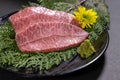 Closeup of slices of raw wagyu beef on evergreen leaves on a board