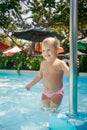 Closeup small blonde girl holds pole in shallow hotel pool