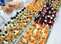 Closeup of small canapes for catering arranged on a mirror plates. Buffet table with cold appetizers and aperitifs with Royalty Free Stock Photo