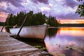 Closeup of small fishing boat at wooden pier on lake surrounded by forest during golden hour Royalty Free Stock Photo