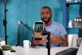 Closeup of smartphone filming influencer sitting down at desk with laptop smiling