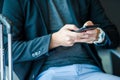 Closeup smartphone in male hands inside in airport. Casual young businessman wearing suit jacket. Young man with Royalty Free Stock Photo