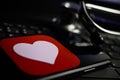 Closeup of smartphone screen with health app heart logo on computer keyboard, blurred stethoscope background