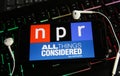 Closeup of smartphone screen with logo lettering of independant online radio broadcast service npr on computer keyboard