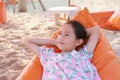 Closeup of smiling Asian young girl relax on orange sofa bed beach on sand at summer holiday Royalty Free Stock Photo