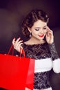 Closeup of a smiling beautiful young woman with shopping bag talking over the cellphone