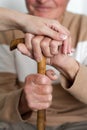 Closeup of smiling senior mans hands and young girl caregiver holding hands on walking stick Royalty Free Stock Photo