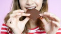 Closeup smiling young Asian woman eating chocolate making a mess chocolate on her mouth on pink background Royalty Free Stock Photo