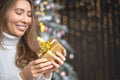 Closeup smiling young blonde woman holding luxury golden Christmas gift box celebrating holiday Royalty Free Stock Photo
