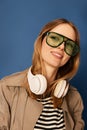 Closeup smiling young woman in wireless headphones listening to music and looking at camera with smile on blue Royalty Free Stock Photo