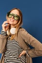 Closeup smiling young woman in wireless headphones listening to music and looking at camera with smile on blue Royalty Free Stock Photo