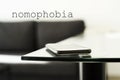 Smpartphone on a glass table and text nomophobia