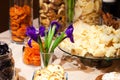 Closeup snacks, dried fruits and nuts in glass bowl, flowers irises in vase, plate with pieces with parmesan cheese. Concept
