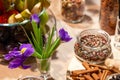 Closeup snacks, purple irises, fresh and dried fruits, red, white and black pepper mix in glass bowl, cinnamon sticks, nuts.